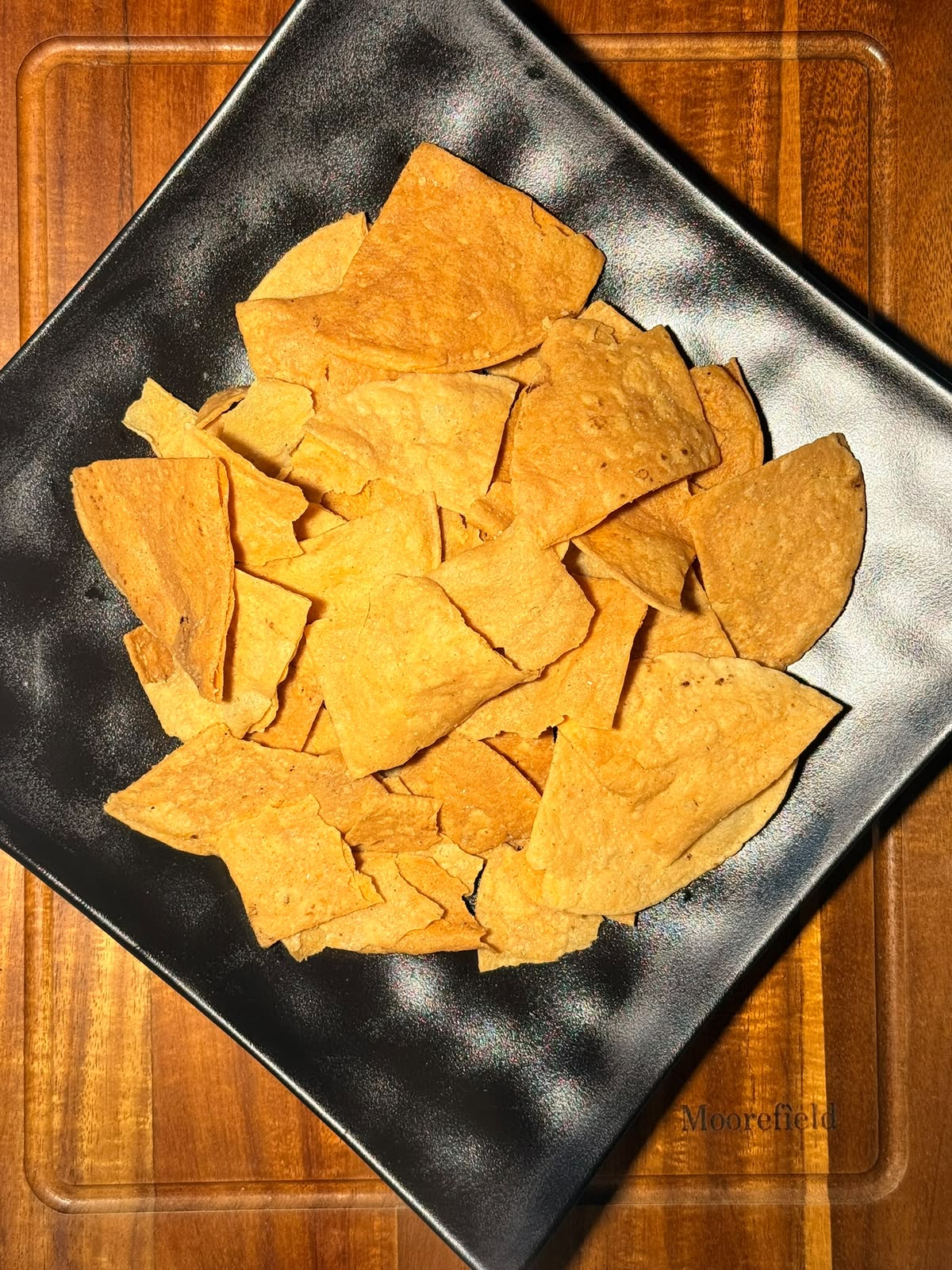 Totopos crujientes dorados en plato negro